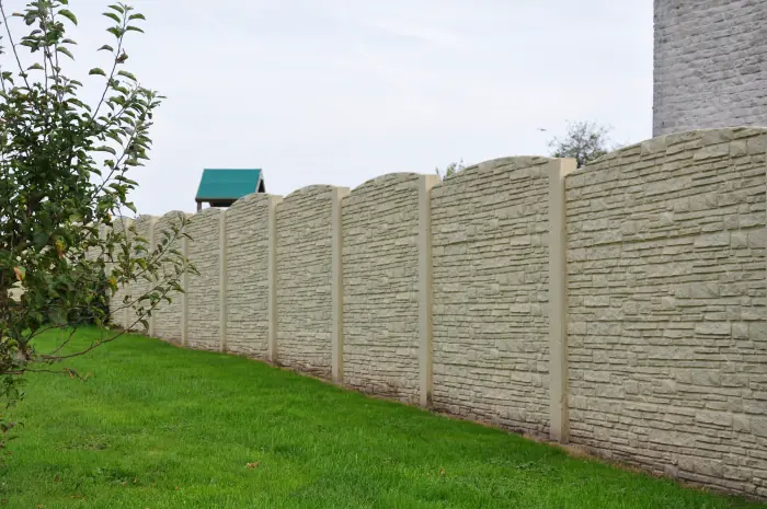 Heller Betonzaun Motiv Rustique mit Steinstruktur an einer Gartengrenze